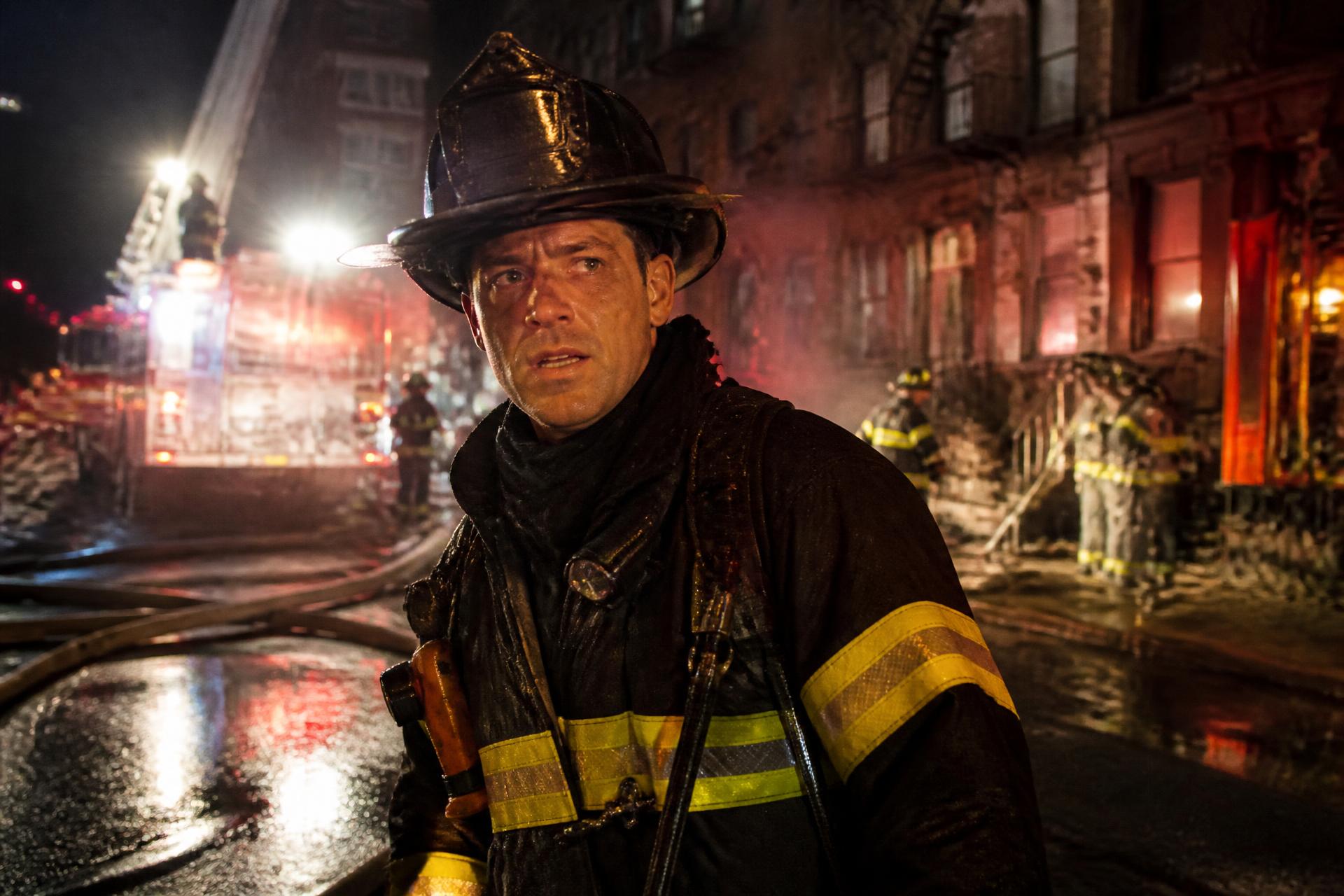 Firefighter working on a wet city street at night under emergency lighting
